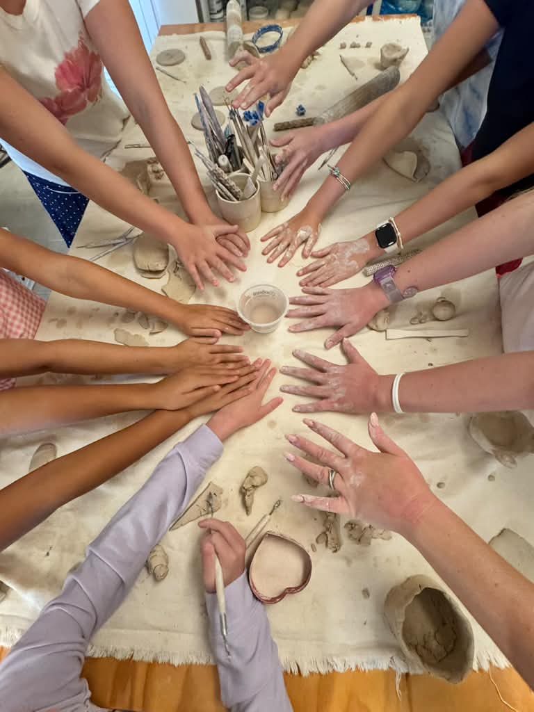 Clay-covered hands in a circle at the studio