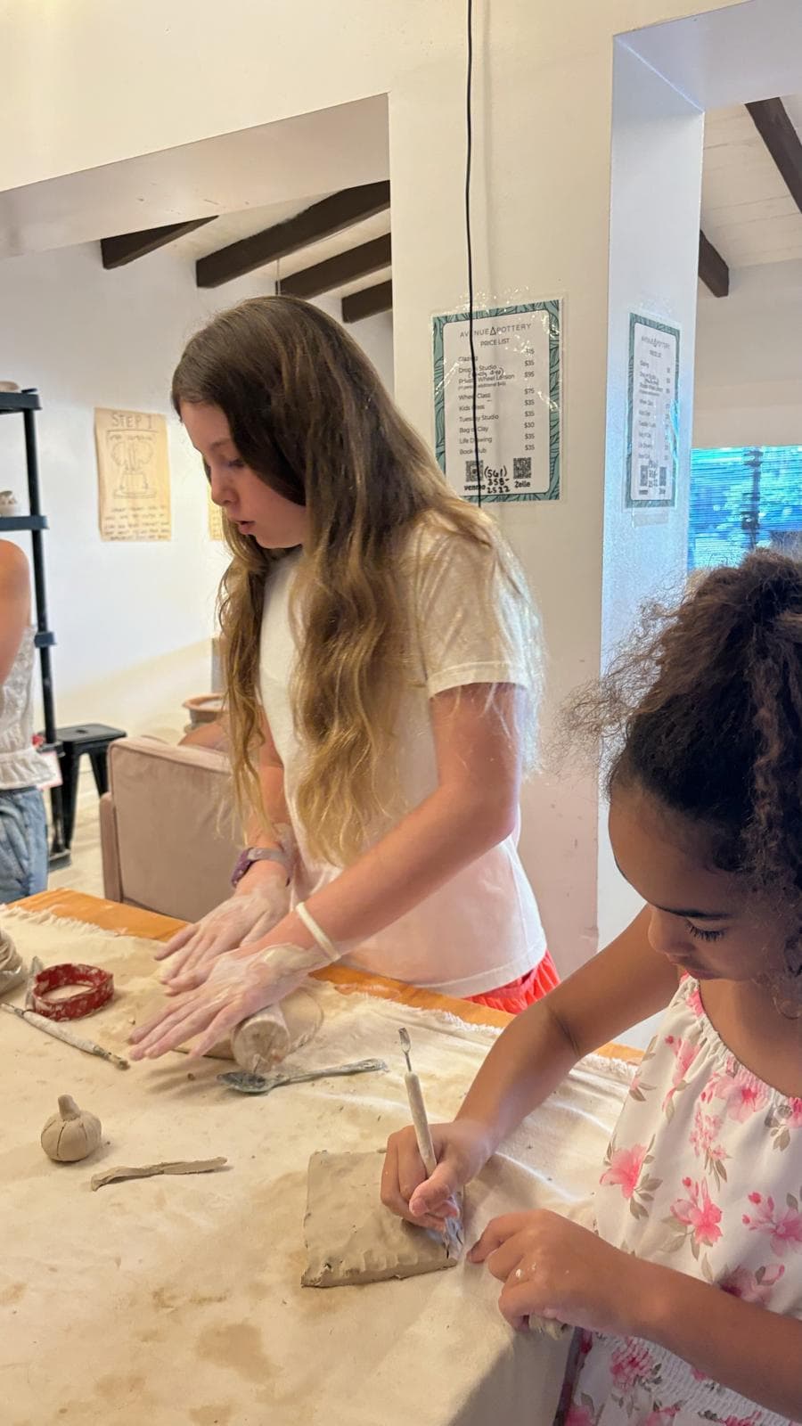 Kids rolling and carving clay at the table