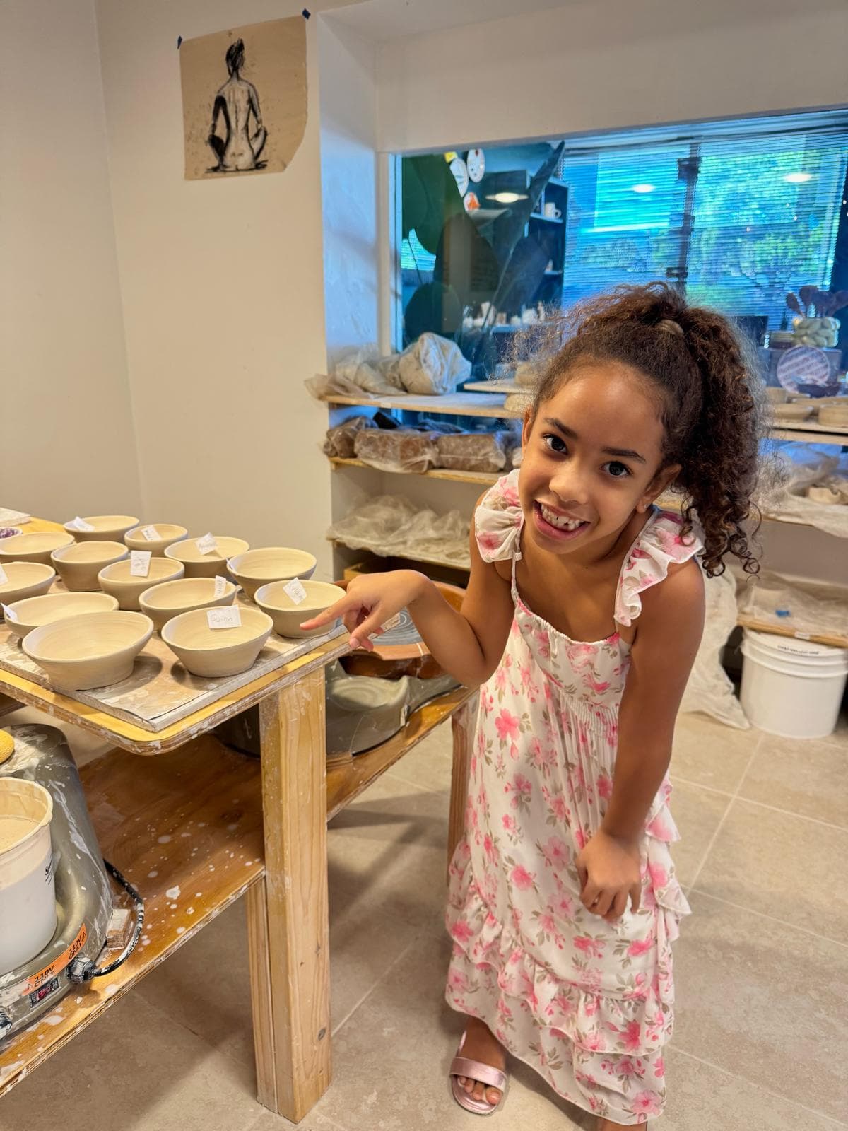 A young potter pointing out her finished bowl