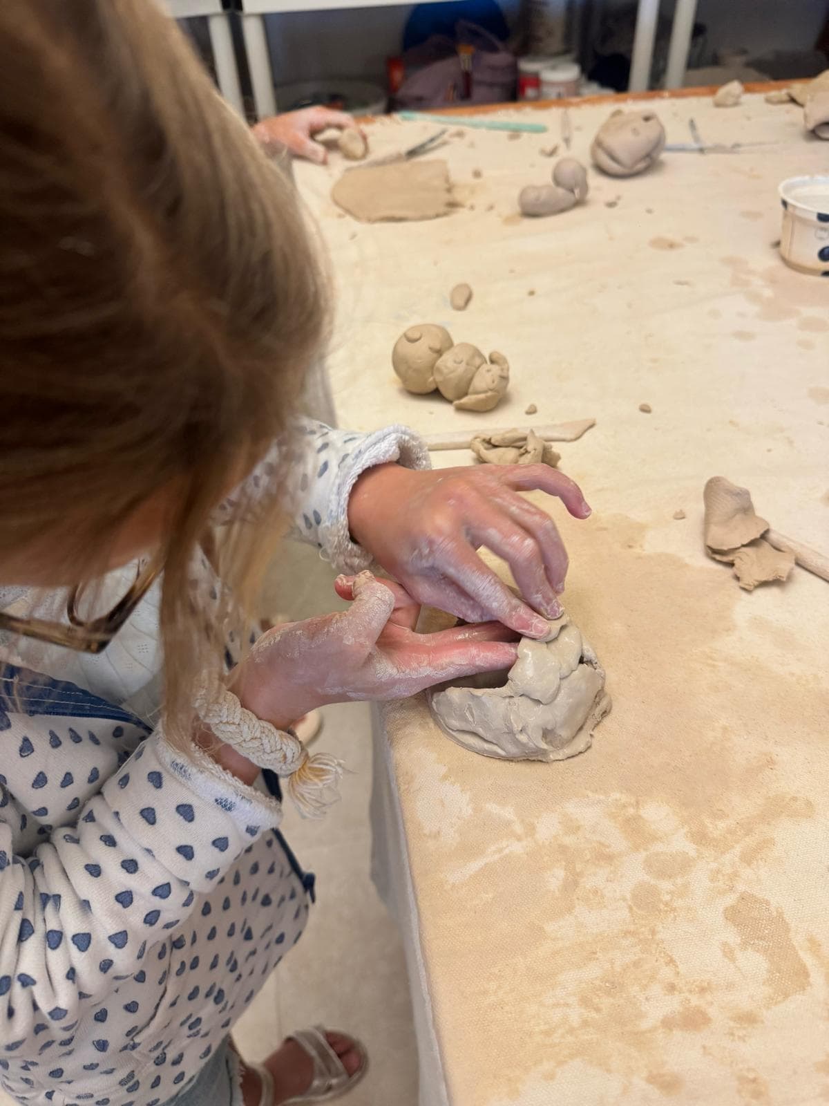 Little hands pinching a clay bowl