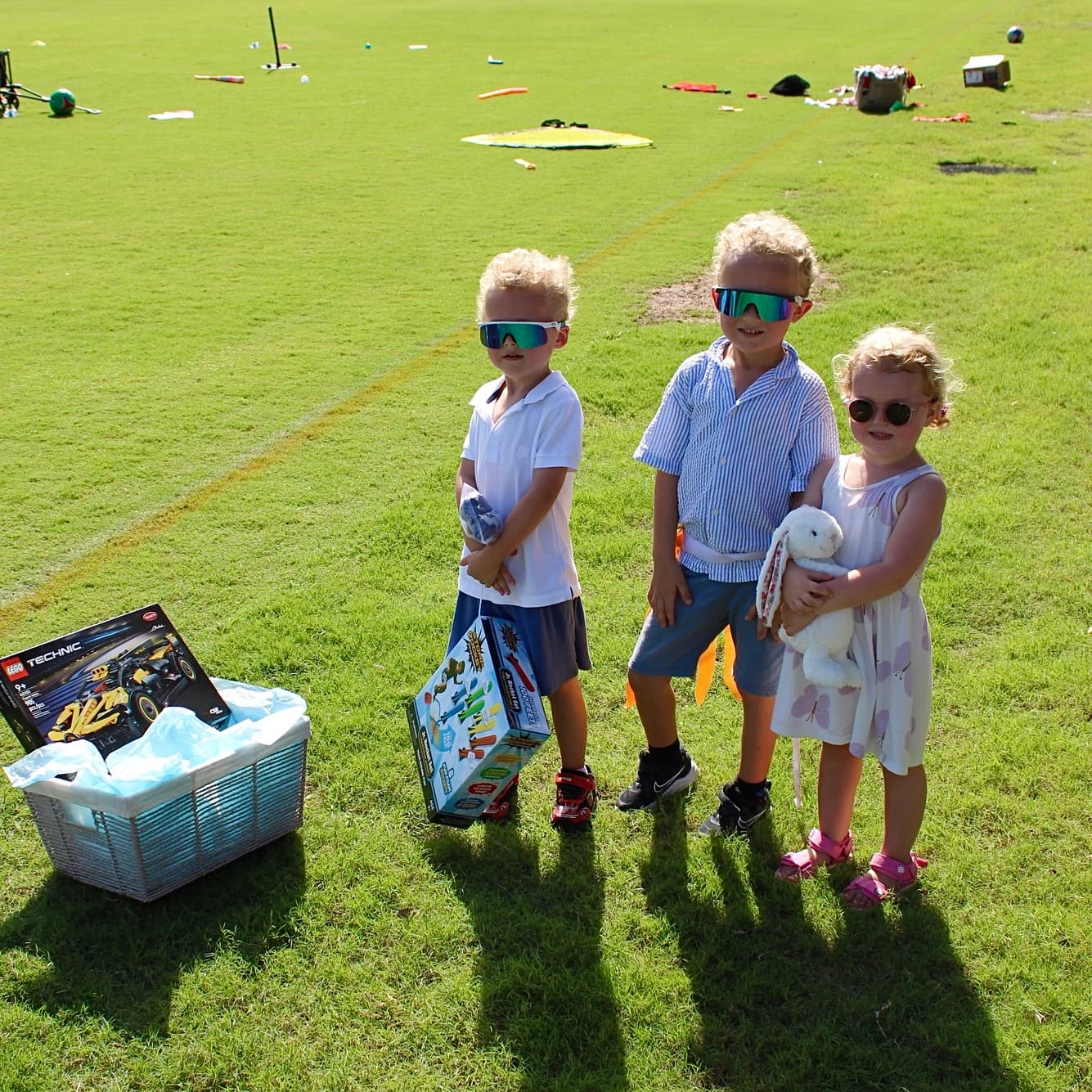 Three kids with prizes on the field at a Village event